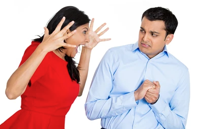 Two people, one leaning forward with hands up and shouting towards a person leaning away