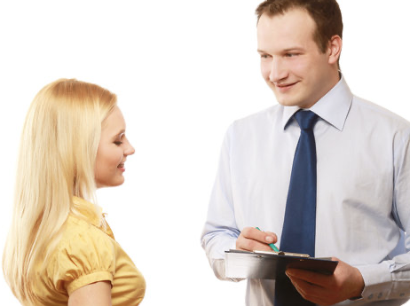 Person with clipboard speaking to someone in a yellow top