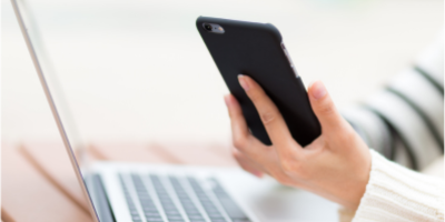 A person holding a smartphone and taking notes