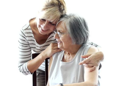 Two people, one sitting down with the other standing behind with their arms over their shoulders