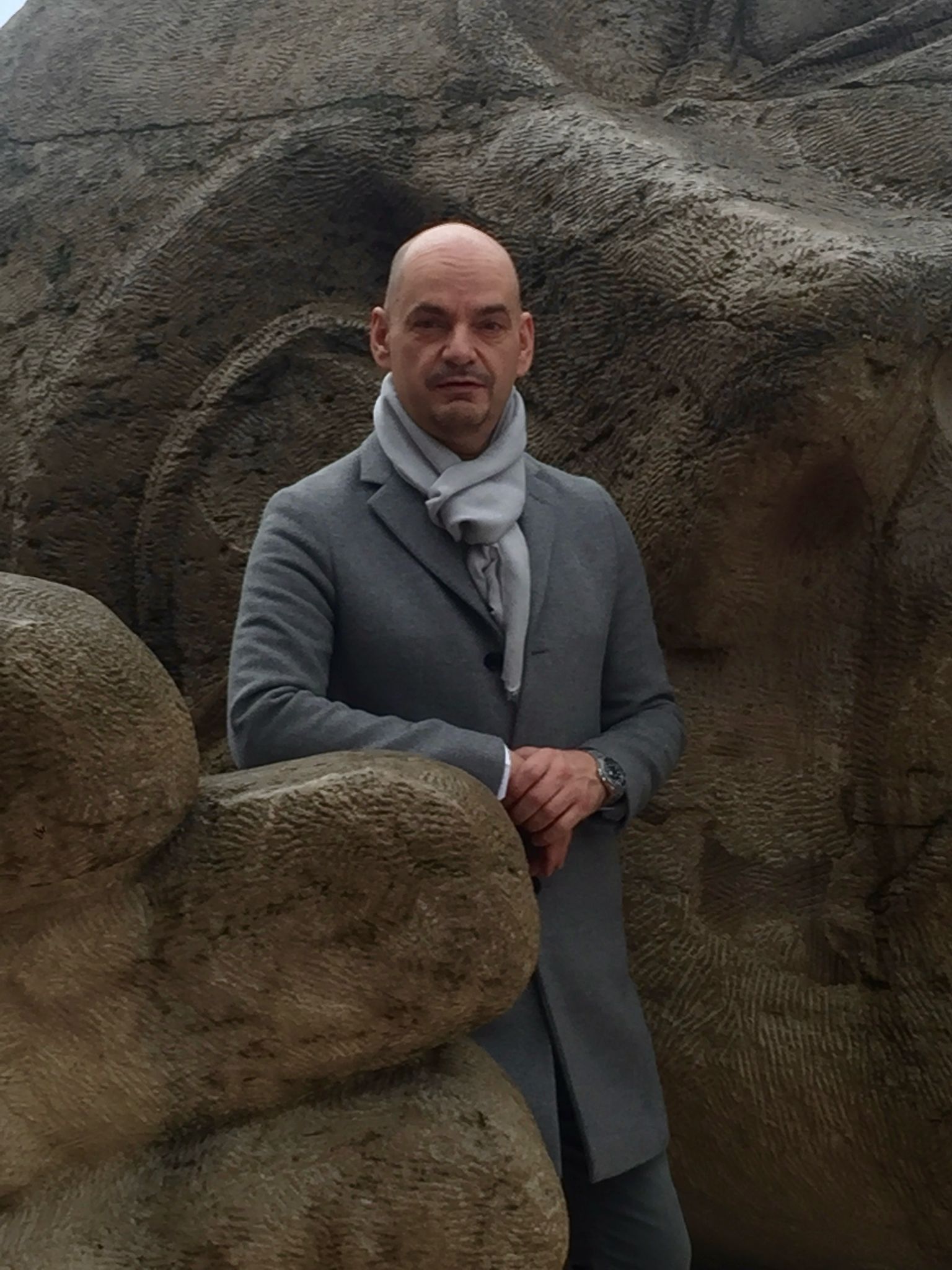 Sean Overett DCS Patient standing next to a large stone statue