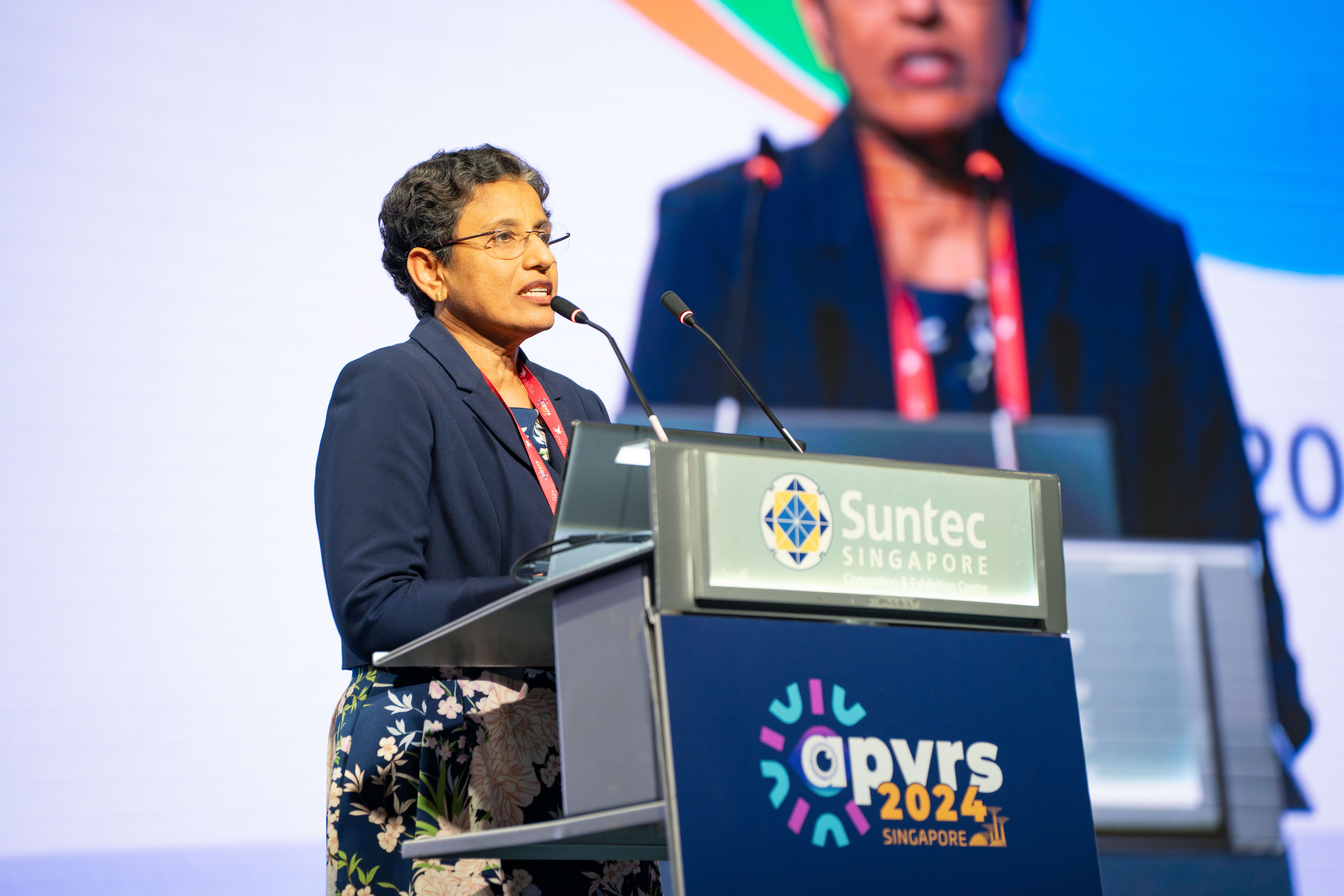 Professor Sobha Sivaprasad at a podium making a speech