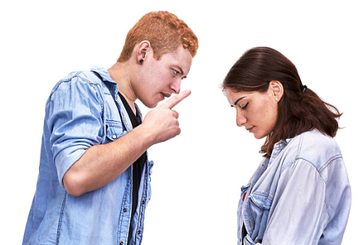 A person looking down and gesturing with a pointing finger at another person who is looking down with a sad expression