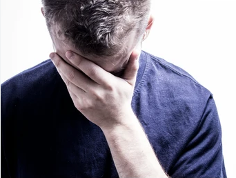 Person looking down with their face in their hand