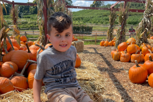 Paediatric patient, Jace, sitting in a pumpkin patch 