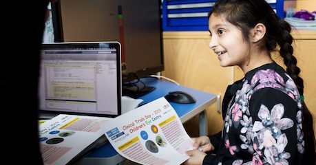 Photo of child in consultation room looking at information on a printed sheet
