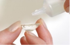 Liquid being placed into a contact lens resting on fingertips