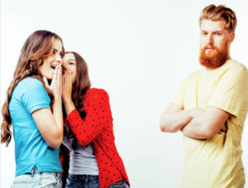 Two people whispering together looking towards another person looking sad